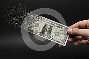 Inflation, dollar hyperinflation with black background. One dollar bill is sprayed in the hand of a man on a black photo