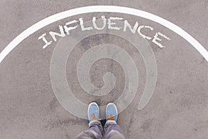 Influence text on asphalt ground, feet and shoes on floor photo