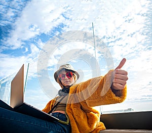 Influencer girl gesturing success showing V for victory, using laptop