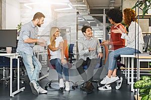 Cheerful millennial team having pleasant conversation in office