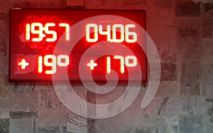 Information board with air temperature, water temperature, time and date, red neon glow, close-up