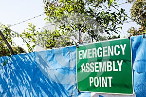 Information sign for emergency assembly point attached on the entrance of construction site.