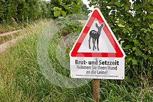 Information sign at the forest in german text means: breed and setteling time. put your dog on a leash.