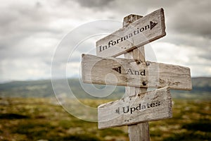 information and updates text engraved on old wooden signpost outdoors in nature