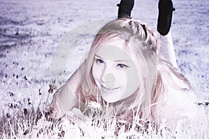 Infrared Portrait of a Hippie Girl lying in a Flower Meadow on a sunny Day