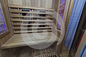 Infrared sauna interior close up view. Wooden walls and bench, ceramic heaters.