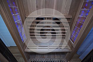 Infrared sauna interior close up view. Wooden walls and bench, ceramic heaters.