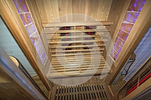 Infrared sauna interior close up view. Wooden walls and bench, ceramic heaters.