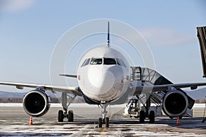 Infrastructure at the airport. A white passenger plane is at the airport with a sleeve attached