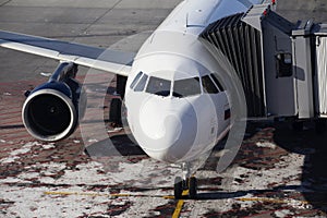 Infrastructure at the airport. A white passenger plane is at the airport with a sleeve attached