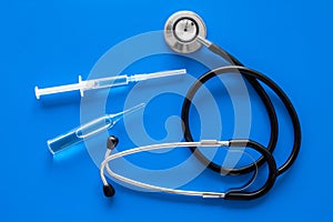 Infuenza, flu vaccine in syringe near stethoscope on blue background top view