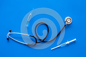 Infuenza, flu vaccine in syringe near stethoscope on blue background top view copy space