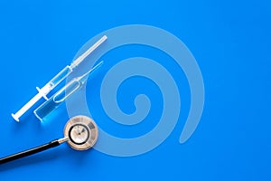 Infuenza, flu vaccine in syringe near stethoscope on blue background top view copy space