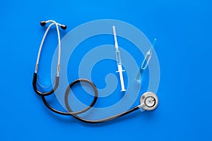 Infuenza, flu vaccine in syringe near stethoscope on blue background top view copy space