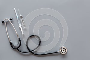 Infuenza, flu vaccine in syringe near stethoscope on grey background top view copy space