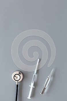 Infuenza, flu vaccine in syringe near stethoscope on grey background top view copy space