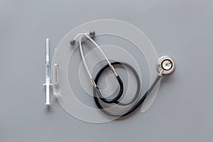 Infuenza, flu vaccine in syringe near stethoscope on grey background top view copy space