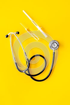 Infuenza, flu vaccine in syringe near stethoscope on yellow background top viewspace for text