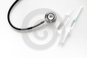 Infuenza vaccine in syringe near stethoscope on white background top view copy space