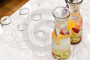 Infused detox water . Fruit infused flavored water, orange slice and kiwi slice in glass jar with glass