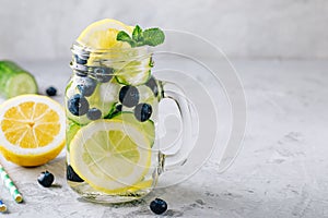 Infused detox water with lemon and cucumber slices, blueberry and mint. Ice cold summer lemonade in glass mason jar