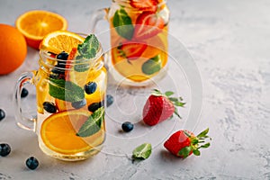 Infused detox water with orange, blueberry, strawberry and mint. Ice cold summer cocktail or lemonade.