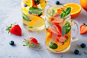 Infused detox water with orange, strawberry, blueberry and mint. Ice cold summer cocktail or lemonade.