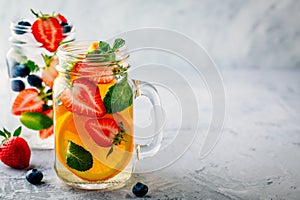 Infused detox water with orange, strawberry, blueberry and mint. Ice cold summer cocktail or lemonade.