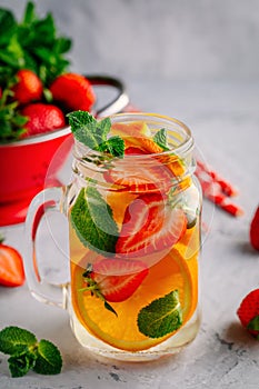 Infused detox water with orange, strawberry and mint. Ice cold summer cocktail or lemonade.