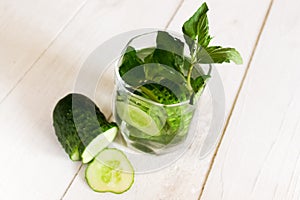 Infused water with cucumber, lime and mint on wood background. Cucumber lemonade