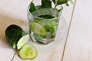 Infused water with cucumber, lime and mint on wood background. Cucumber lemonade