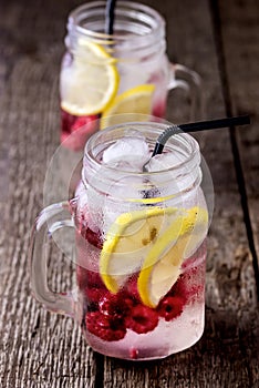 Infused Water with Lemon and Raspberry Healthy Detox Drink Cold Berry Fruit Lemonad in Glass Jars Wooden Background Vertical