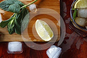 Ingredients for an alcoholic cocktail: ice, mint, lemon, lime. Rum, whiskey, cognac