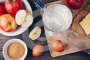 Ingredients for apple pie cooking with fresh red apples, butter, flour, eggs, brown sugar and spices