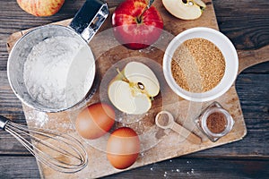 Ingredients for apple pie cooking with fresh red apples, flour, eggs, brown sugar and spices