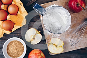 Ingredients for apple pie cooking with fresh red apples, flour, eggs, brown sugar and spices