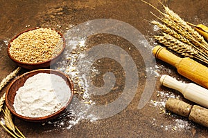 Ingredients for baking bread: wheat ears and a bowls of flour and grains