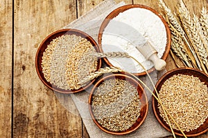 Ingredients for baking bread: wheat ears and a bowls of flour and grains