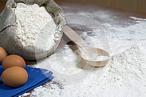 Ingredients for baking bread. Wooden spoon, eggs and flour on the table