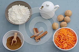 Ingredients for baking carrot cake. Flour, grated carrots, milk, walnuts, spices are located on the kitchen table in gray. Carrot