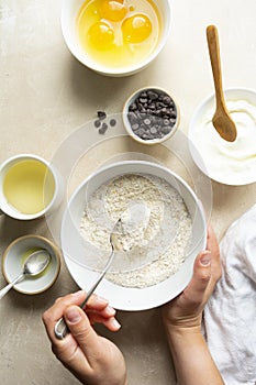 Ingredients for baking, cooking dessert or pastry. Top view, woman's hand holding a bowl with white flour