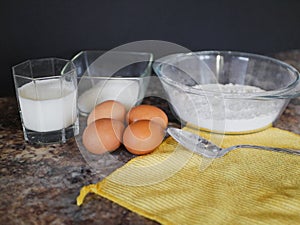 Ingredients for baking dough. flour, eggs, milk. Baking ingredients. Spoon on a marble table. Preparation for cooking