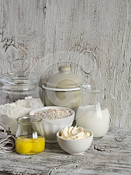 Ingredients for baking - flour, milk, butter, eggs on a light wooden table. Free space for text.