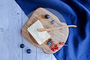 Ingredients for baking lie on a light wooden background with a blue kitchen towel. butter, berries and wooden