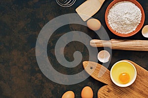 Ingredients for baking rye bread , rye flour, rolling pin, cutting board, eggs, spatula, whisk. Top view, dark rustic background,