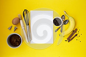 Ingredients for baking with white paper for text, baking utensile on yellow background - flour, wooden spoon, rolling pin, eggs, photo