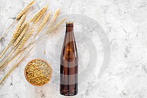 Ingredients for beer. Malting barley near beer glasses and bottle on grey background top view copyspace
