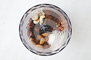 Ingredients for brownie energy bites in the food processor on white wooden table.