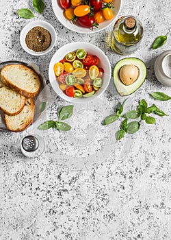 Ingredients for bruschetta - tomatoes, avocado, basil, olive oil, bread. On a light background