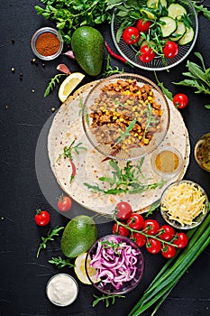 Ingredients for burritos wraps with beef and vegetables on black background